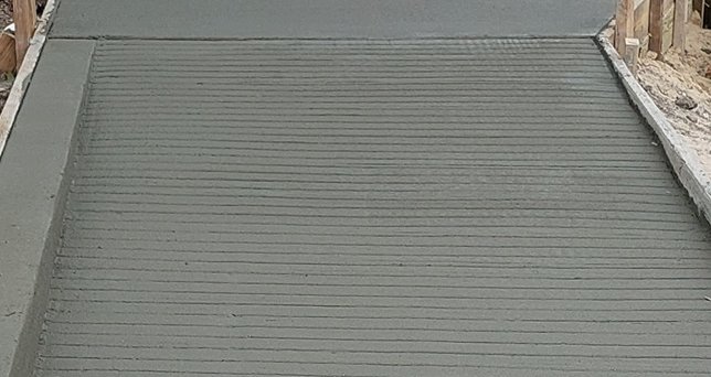 Freshly poured concrete sidewalk section inside wood forms