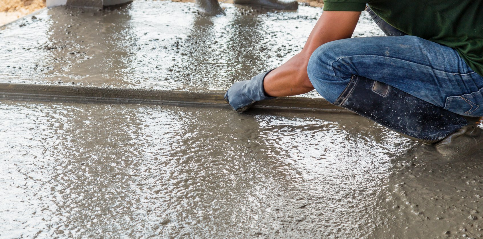 Crew member leveling fresh concrete with a screed board