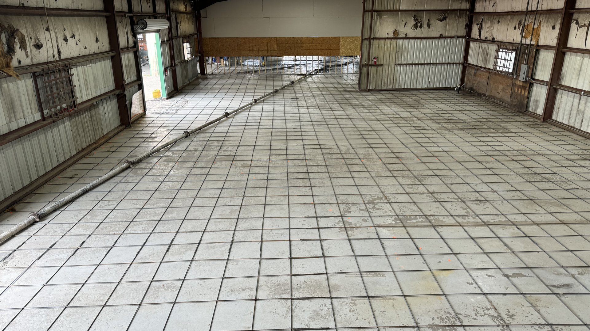 Steel reinforcement grid laid across the floor of a metal building before a concrete slab pour