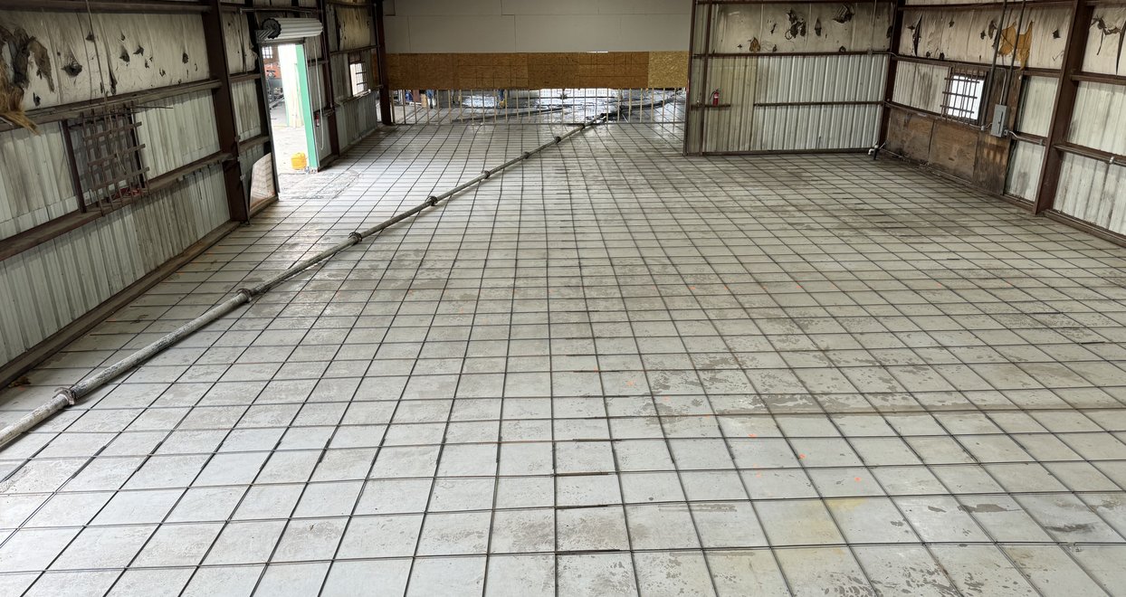 Rebar grid laid out for a commercial slab inside a metal building
