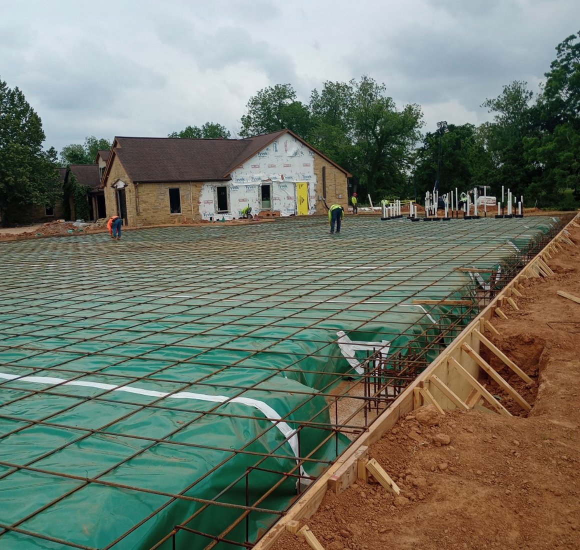 Steel rebar grid over a green vapor barrier inside wood forms, ready for a large slab foundation pour