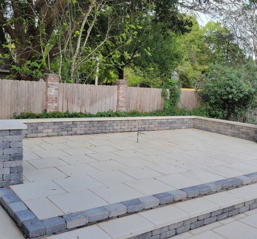 Gray block retaining wall with capped columns around a raised paver patio